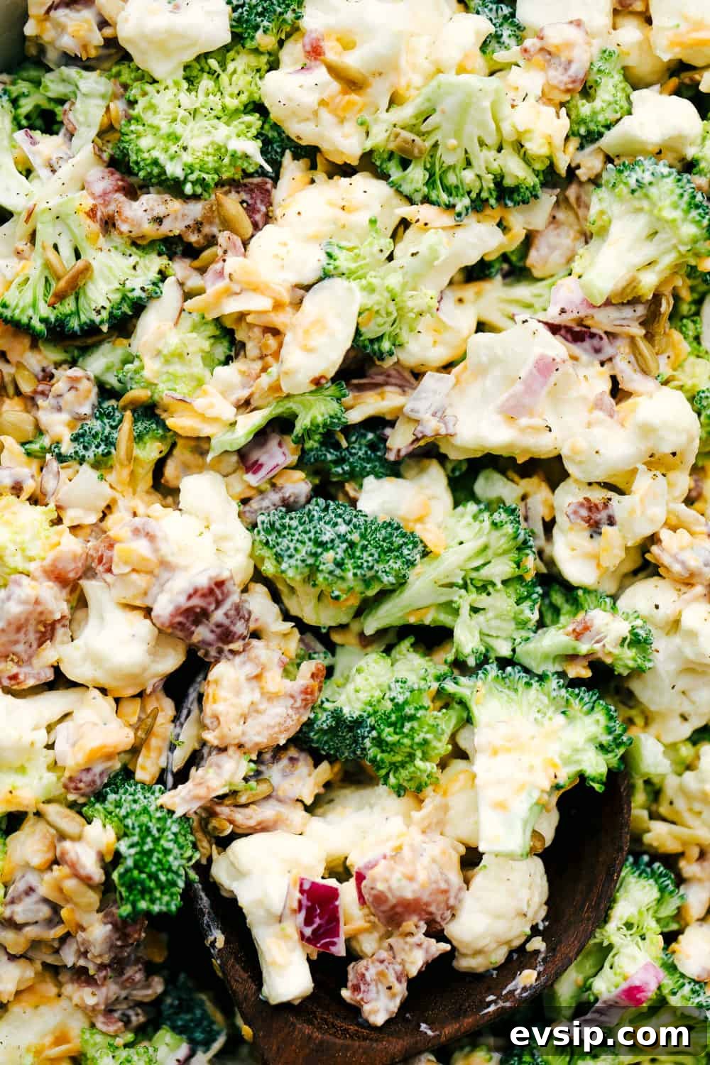 Cauliflower broccoli salad is filled with fresh florets and red onions, bacon pieces with chunks of cheese making this the perfect side salad. Cauliflower broccoli salad photo with shredded cheese and bacon shown throughout.