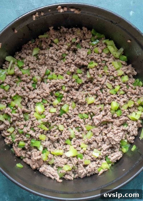 browned ground beef with chopped bell peppers and jalapenos in a cast iron dutch oven