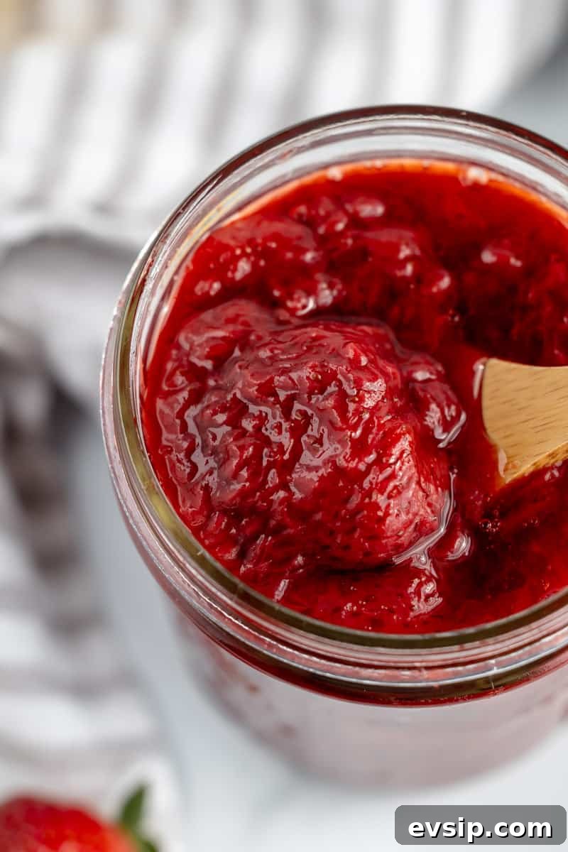 Homemade Strawberry Compote: Quick Recipe for Desserts 15 A wooden spoon scooping strawberry compote out of a jar