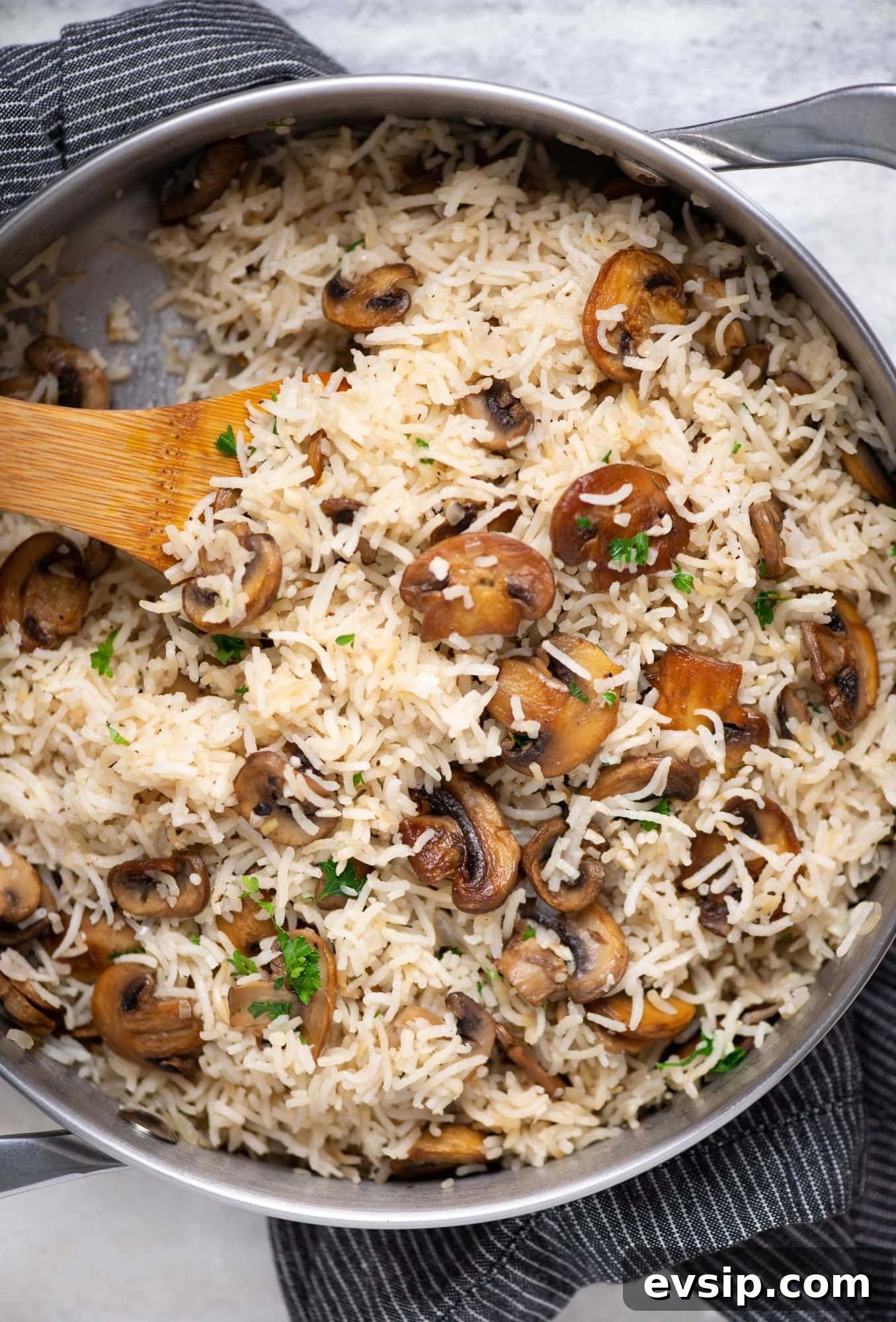Mushroom rice made as a one-pot dish shown in a pot with brown colored rice and sauteed mushrooms.
