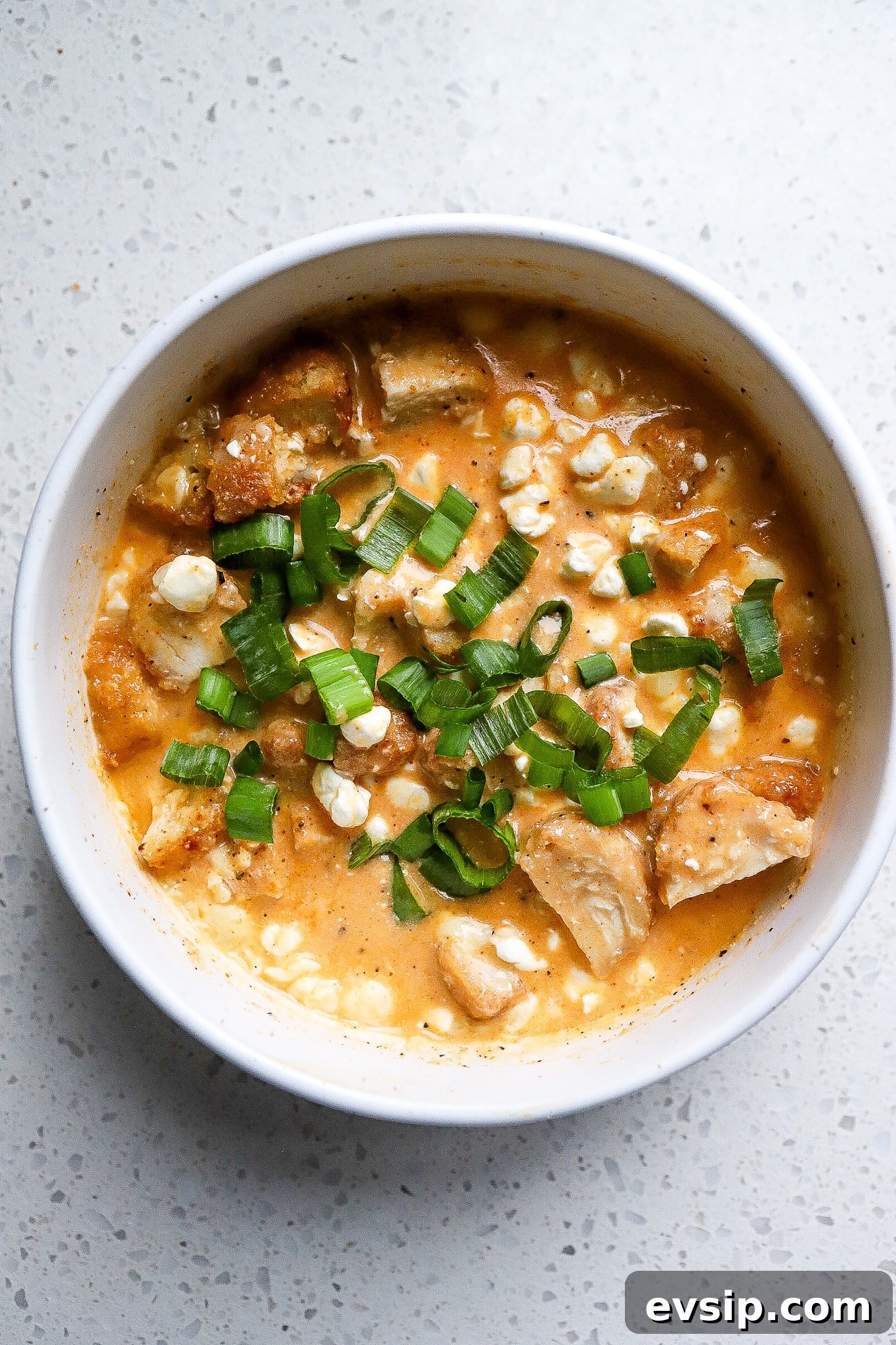 Buffalo Chicken Cottage Cheese Bowl for High-Protein Meals 2 Top down view of buffalo chicken cottage cheese bowl with green onions on top.