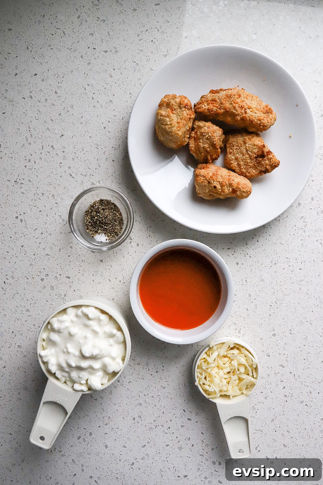 Buffalo Chicken Cottage Cheese Bowl for High-Protein Meals 4 Top down view of a bowl of chicken fingers, seasonings, mozzarella cheese, and buffalo sauce.
