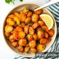 A bowl of roasted harissa potatoes garnished with parsley and a lemon wedge.