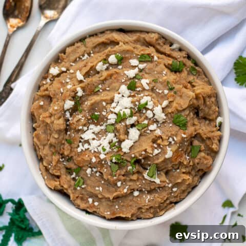 recipe for refried beans made in the instant pot in a white bowl with cilantro