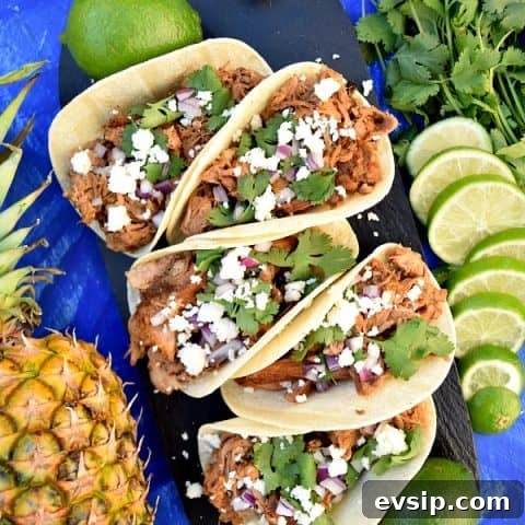 Slow Cooker Chipotle Pineapple Carnitas on a serving platter topped with cheese, onions, and cilantro