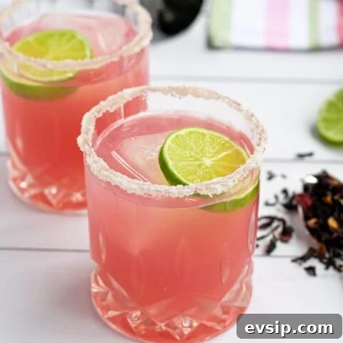 a glass of the best hibiscus margarita recipe with a salted-rim and a slice of lime
