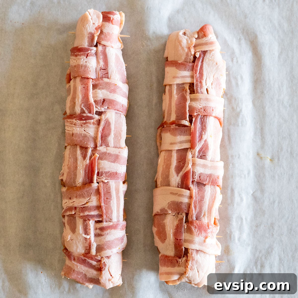 two bacon-wrapped pork tenderloins on table.