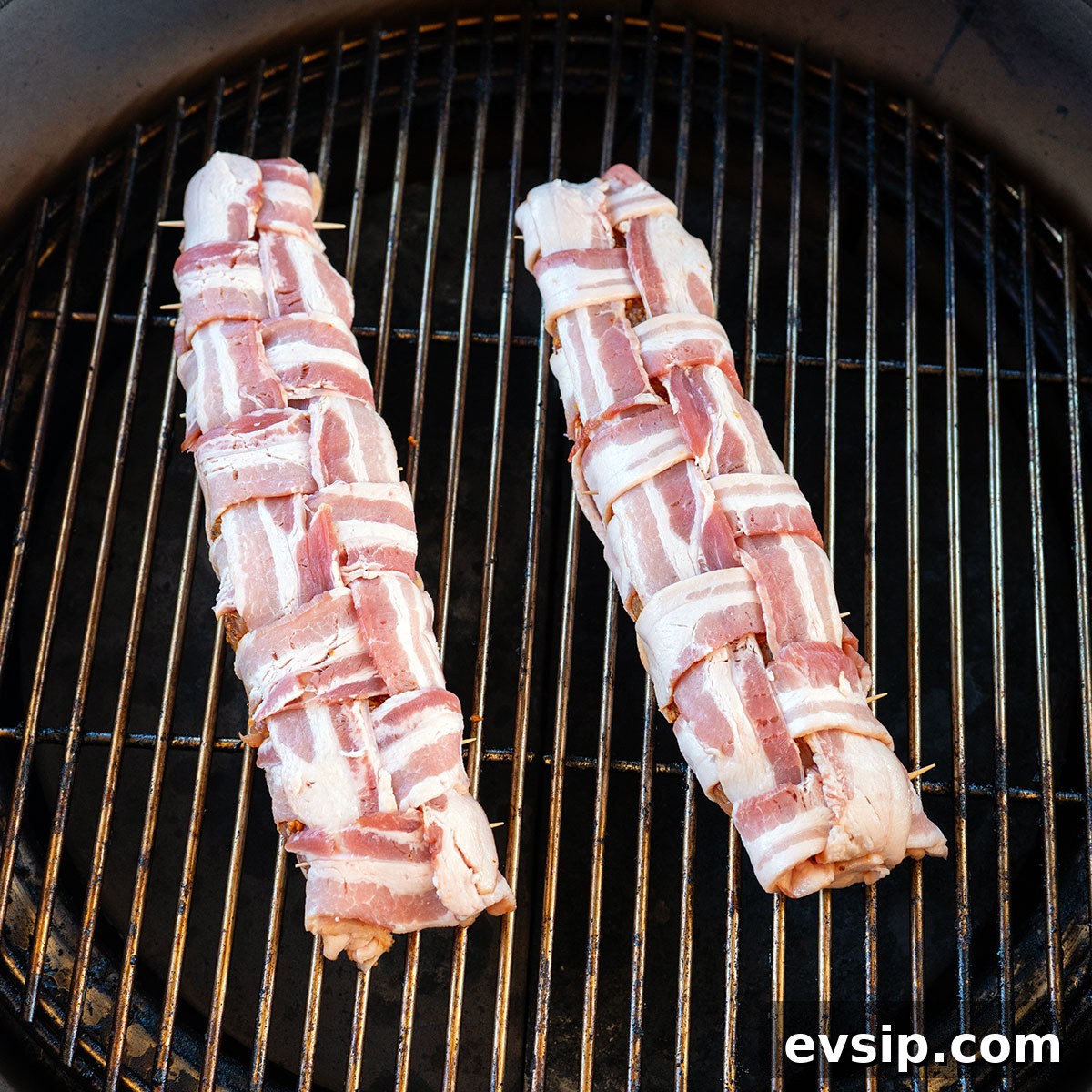 two bacon-wrapped pork tenderloins on grill.
