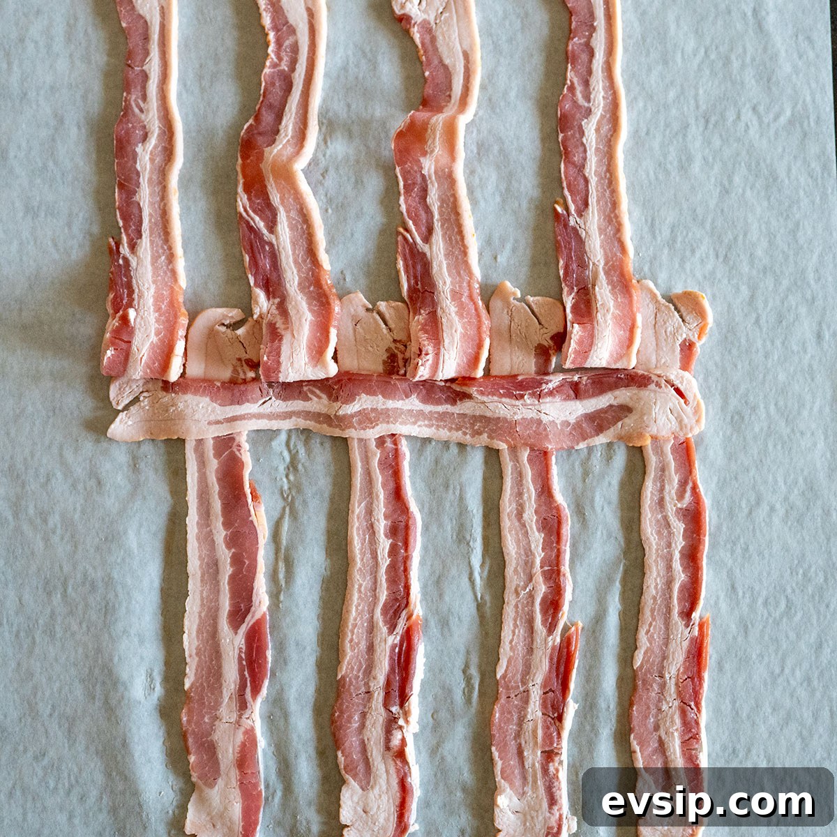 odd pieces of bacon folded back with one strip laying across strips that are down.