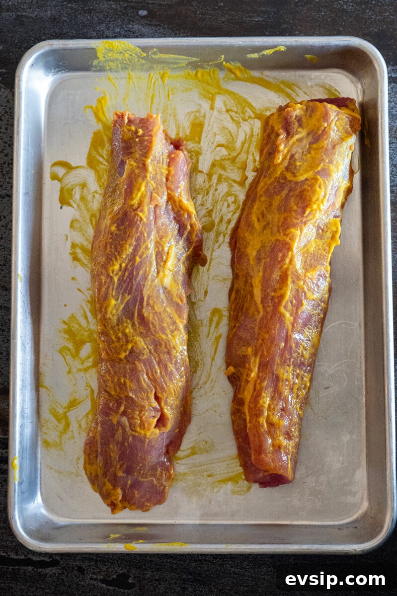 two pork tenderloins rubbed with mustard.