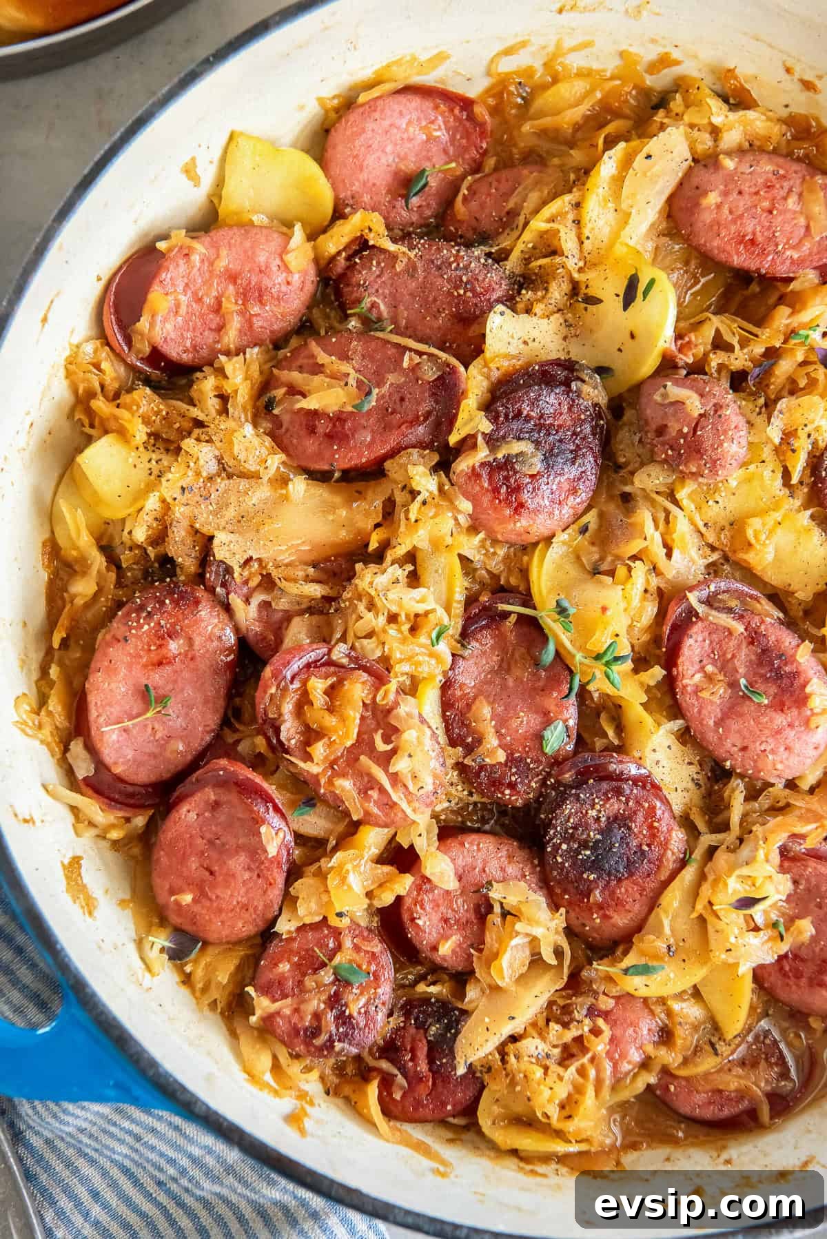 Kielbasa and sauerkraut with apples in a skillet.