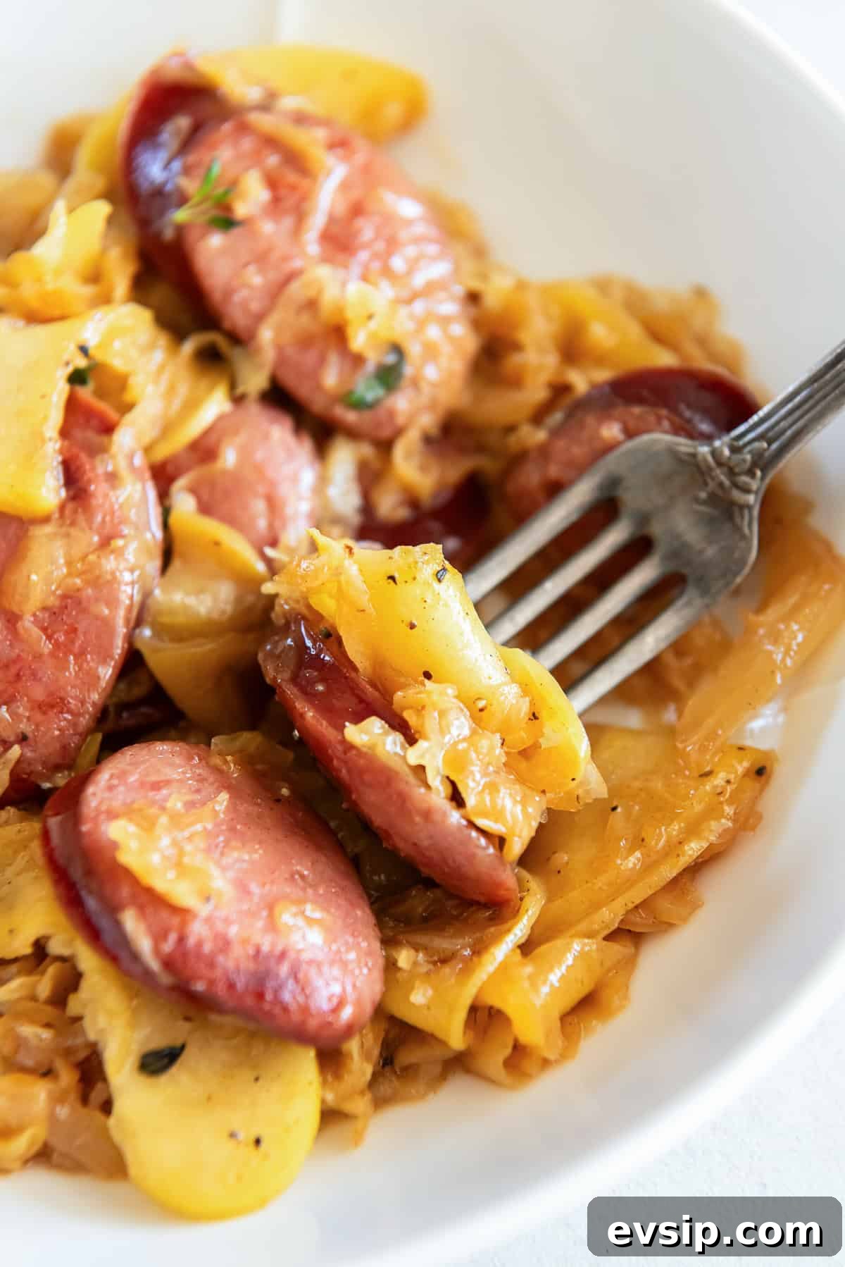 A fork in a bowl of kielbasa and sausage.