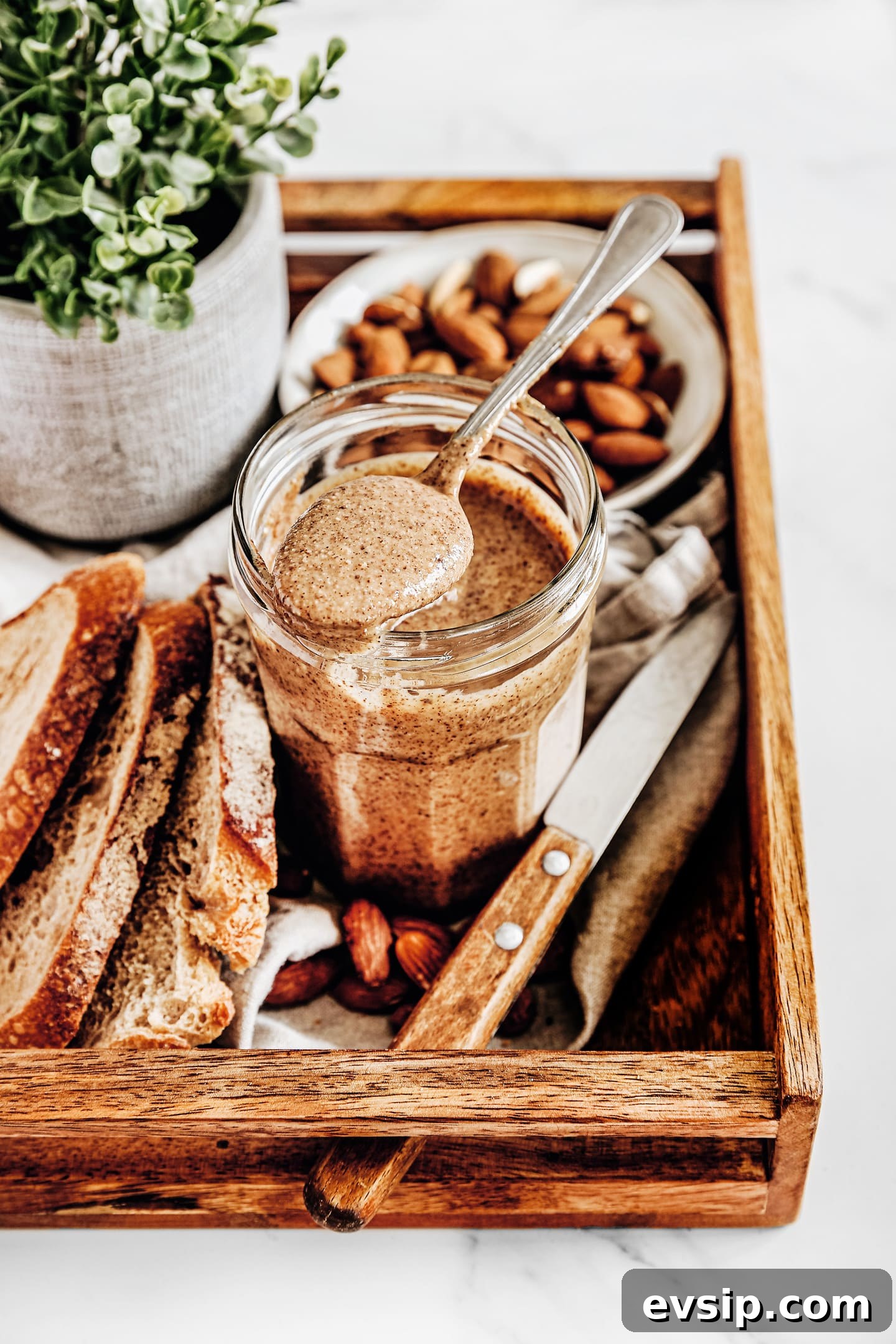 almond butter on a wood board with a teaspoon and bread