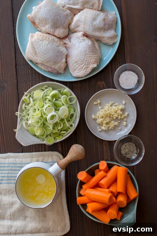 chicken thighs, garlic, salt and pepper, carrots and butter on a wooden table.