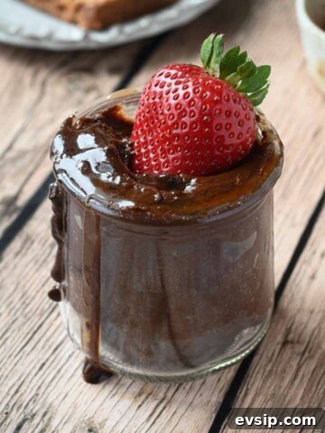 Close-up of a strawberry dipped inside a jar of chocolate tahini spread.