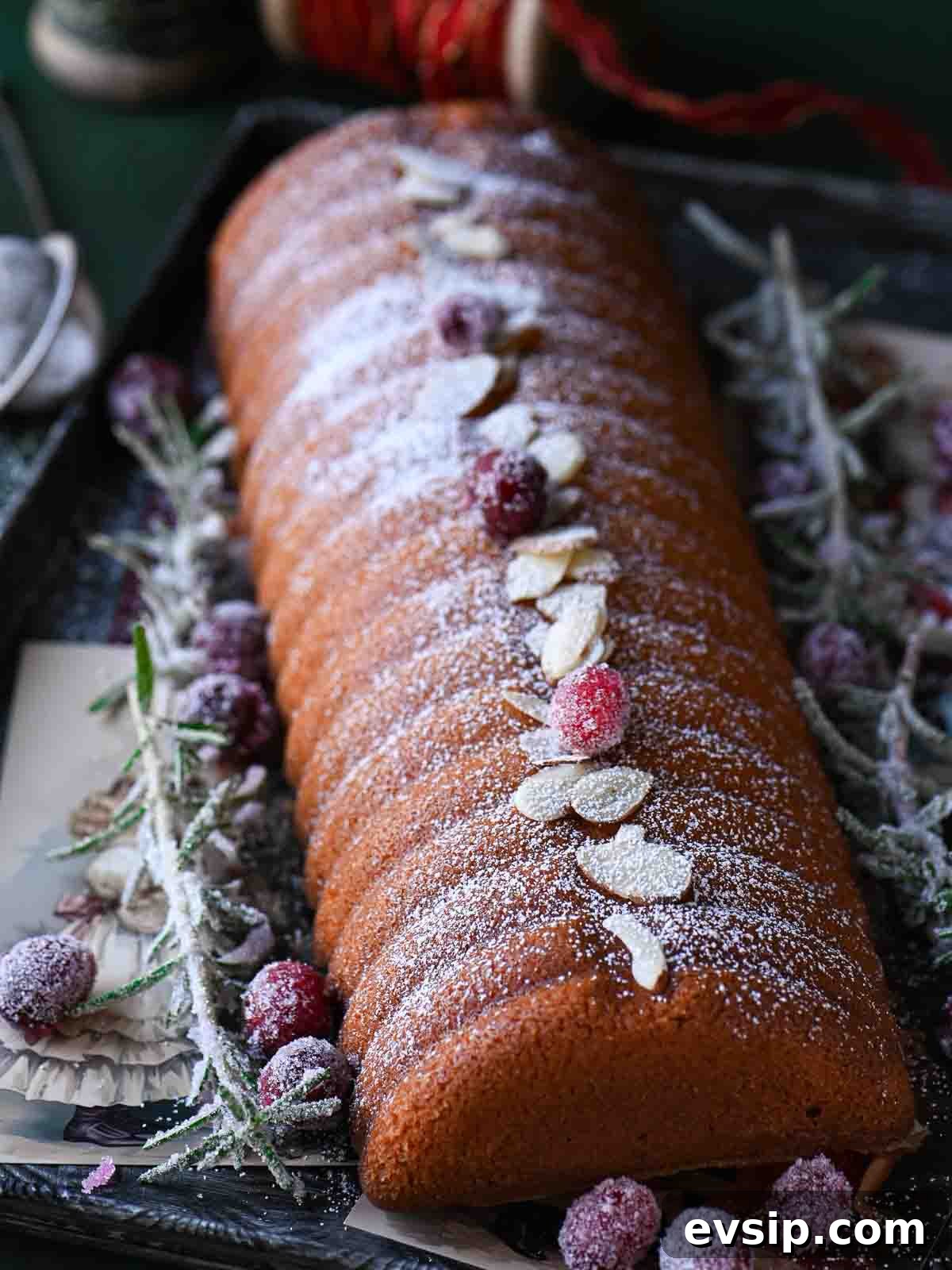 Almond cake close-up with almonds, cranberries and sugared rosemary.