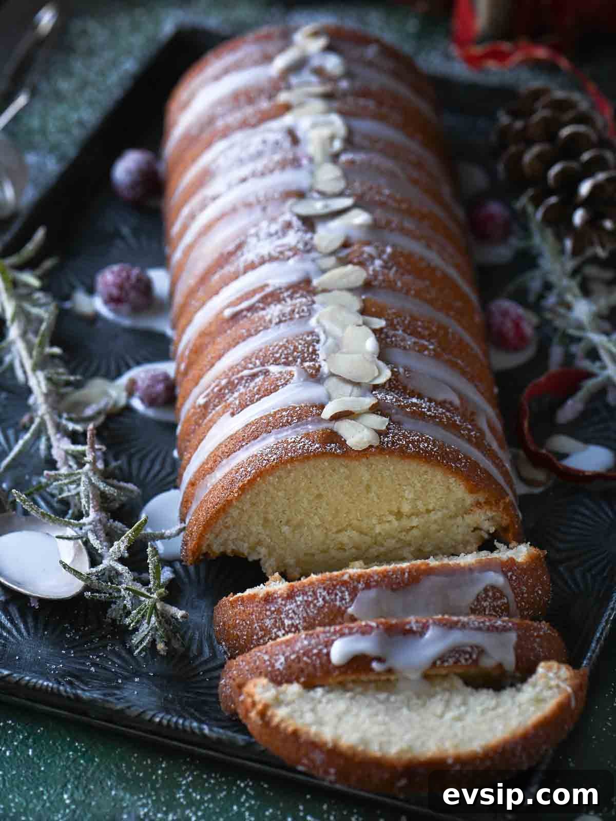 Angled view on an almond cake with icing on top and sugared cranberries.