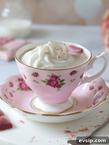 Ruby hot chocolate in a pink floral cup with whipped cream on top.
