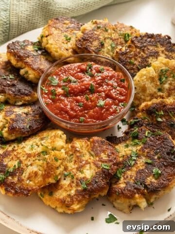 Fried cauliflower cakes on a plate with marinara sauce.