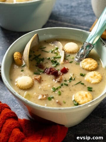 New england clam chowder in a bowl garnished with chives and oyster crackers.