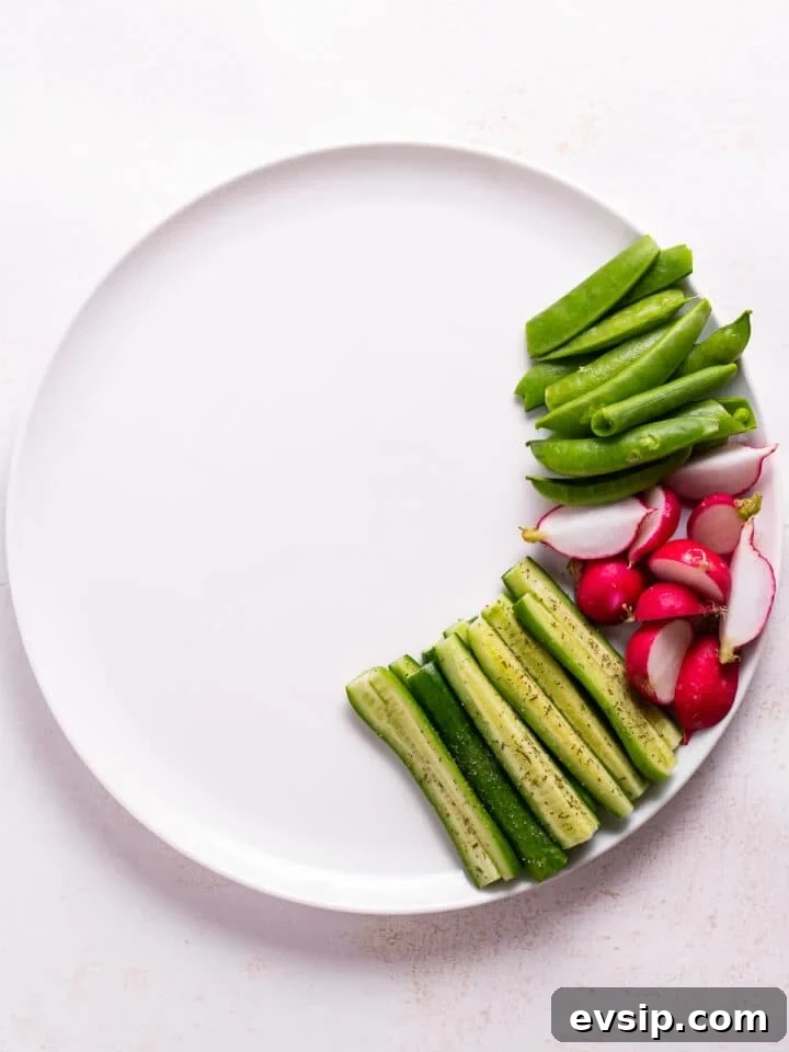 snap peas, radishes and cucumbers on a white plate