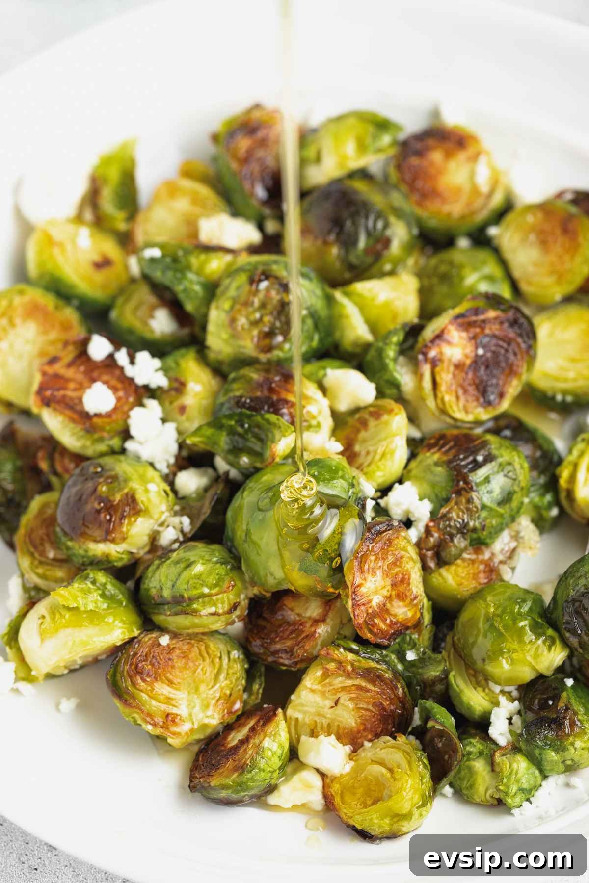 Roasted Brussels Sprouts with Goat Cheese and Honey Glaze 2 Honey being drizzled over cooked Brussels sprouts.