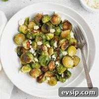 Roasted Brussels Sprouts with Goat Cheese and Honey Glaze 11 Roasted Brussels sprouts with goat cheese on a round plate with a vintage fork.