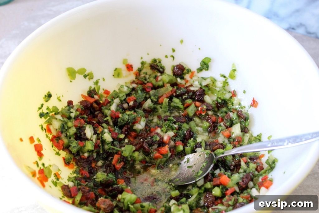 a large bowl with chopped fresh vegetables being mixed with a lemon olive oil vinaigrette 