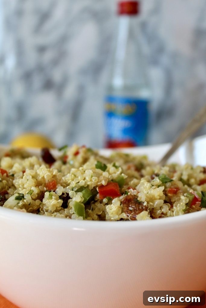 a close up of quinoa with bits of chopped red and green peppers and raisins
