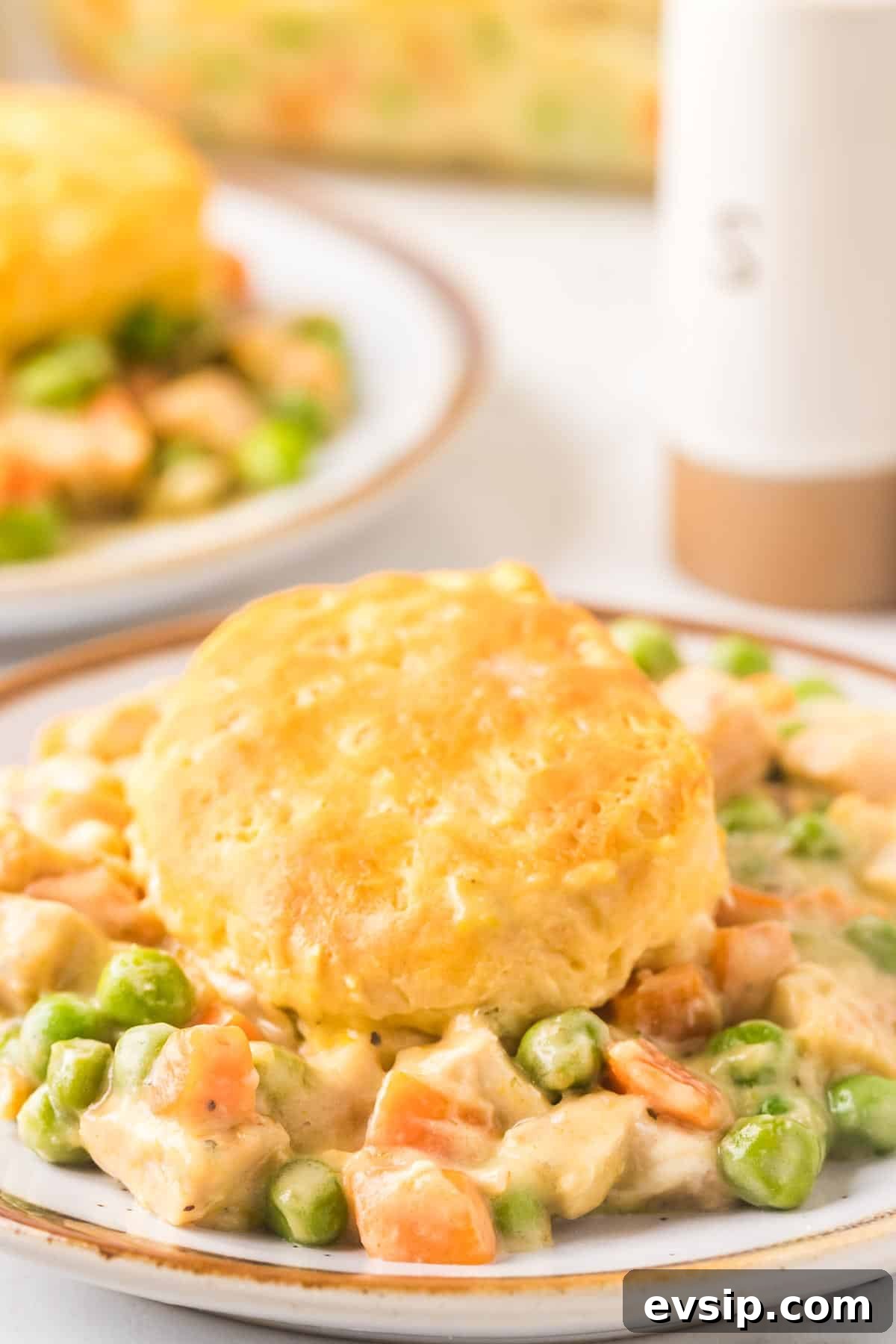 Dinner plate of chicken pot pie casserole with a biscuit on top