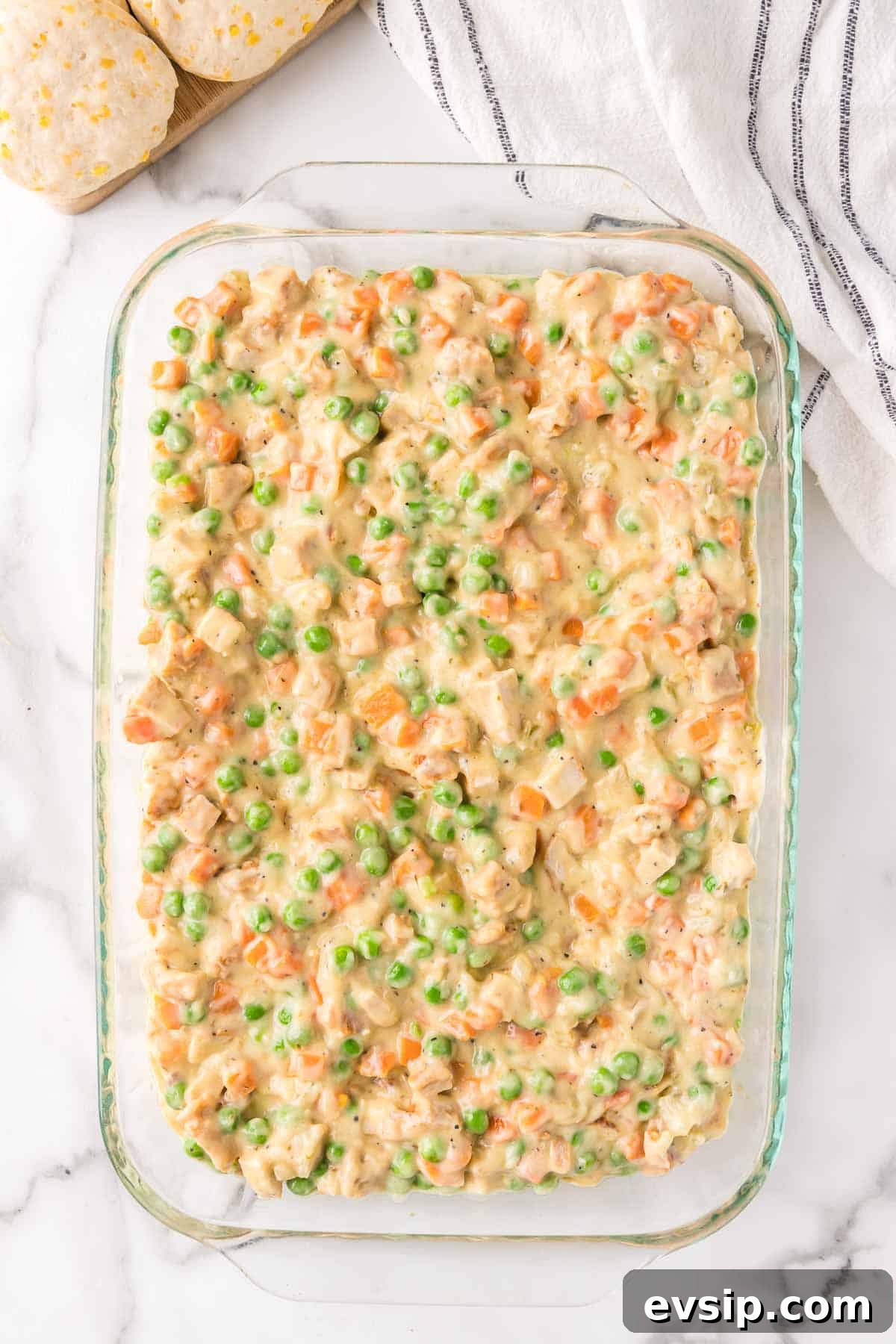 The chicken pot pie filling is spread evenly in a 9 by 13 inch baking dish