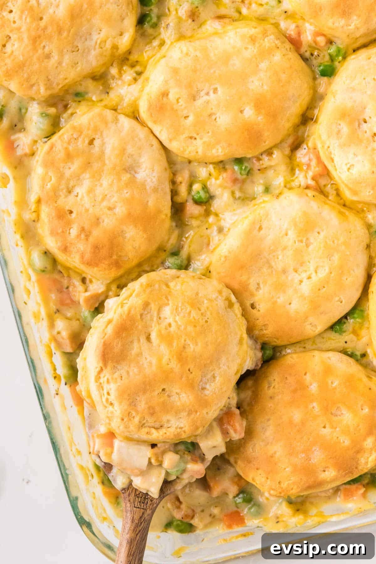 Easy chicken pot pie casserole with biscuits being served with a large spoon