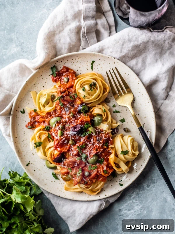 Lemon Shrimp Pasta al Limone — Creamy Citrus Pasta Recipe 9 Plate of pasta topped with puttanesca sauce, with a side of red wine and parsley.