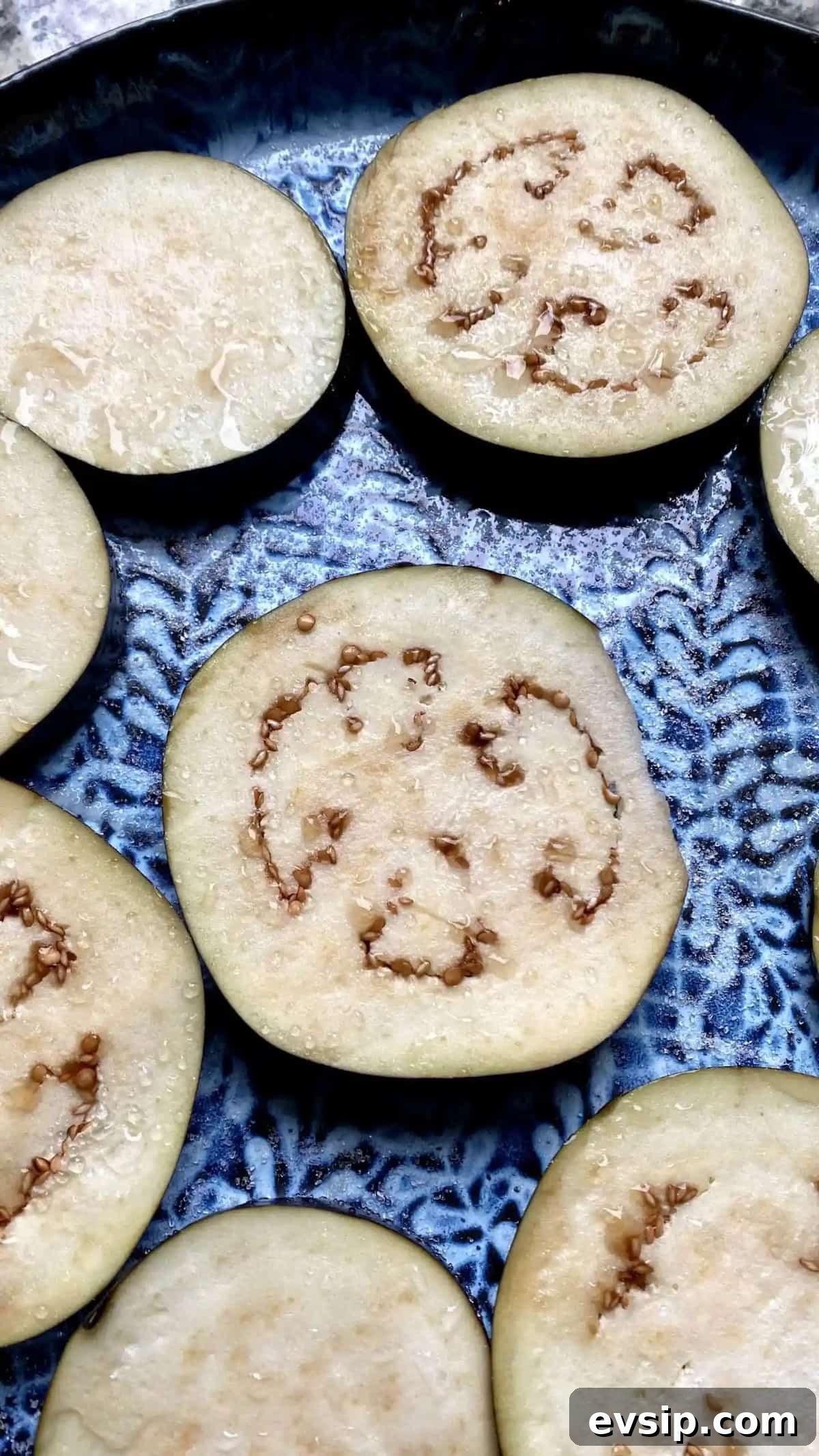 Eggplant slices on a plate with salt to remove its excess water.