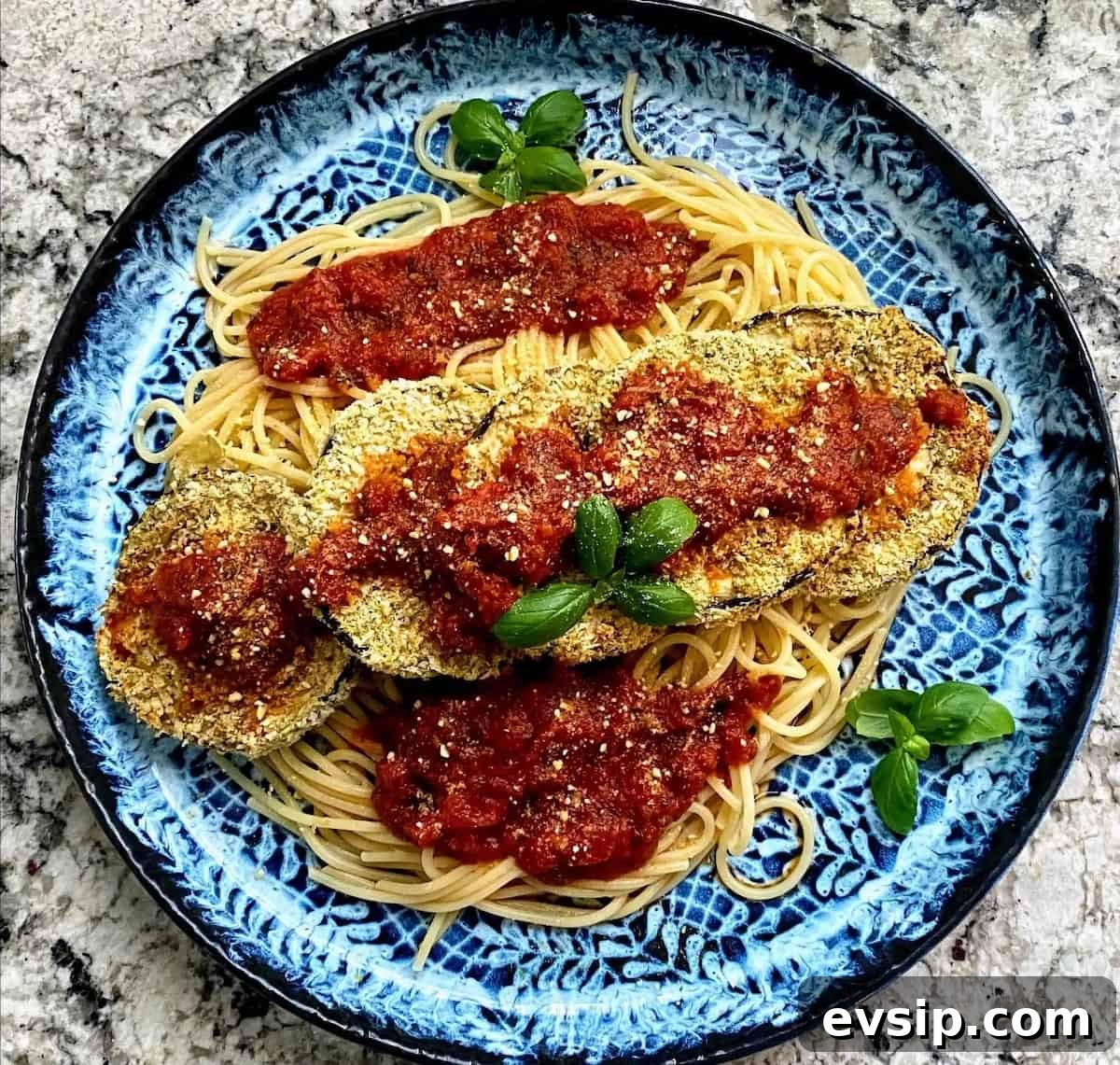 The recipe is served over spaghetti noodles on a plate garnished with basil.