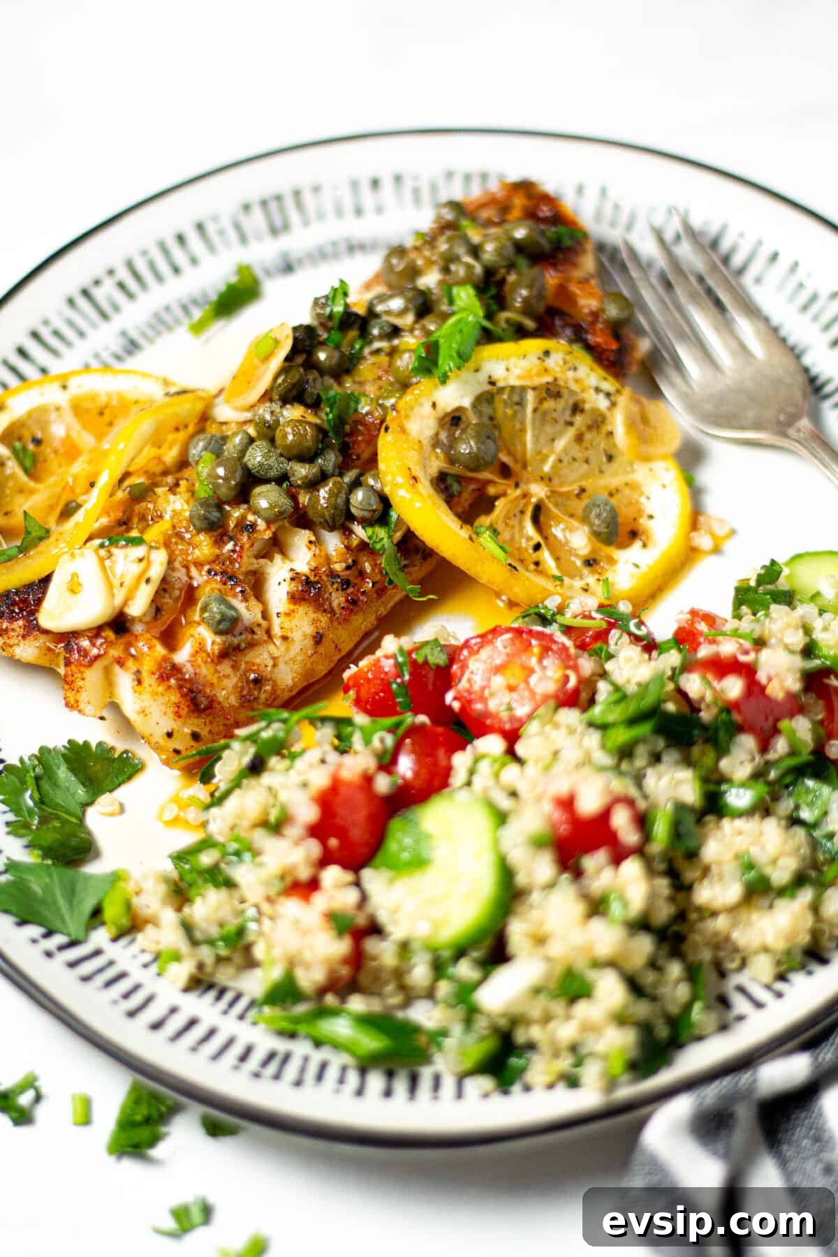 A plate filled with quinoa tabbouleh and Mediterranean cod garnished with fresh parsley 