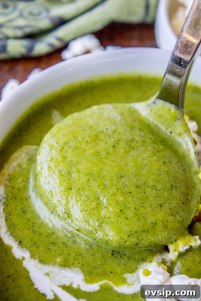 Creamy Zucchini Soup Topped with Crunchy Popcorn Garnish 3 creamy zucchini soup being lifted by a spoon.