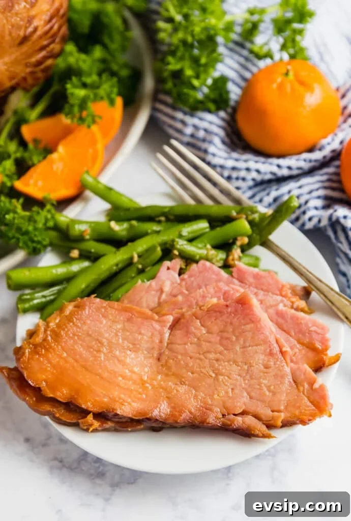 Sliced ham on a plate with green beans.