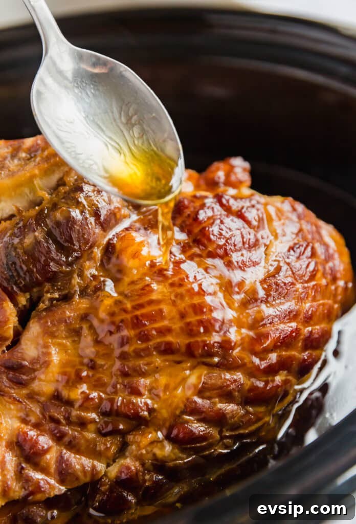 Spoon pouring juices on a spiral ham.