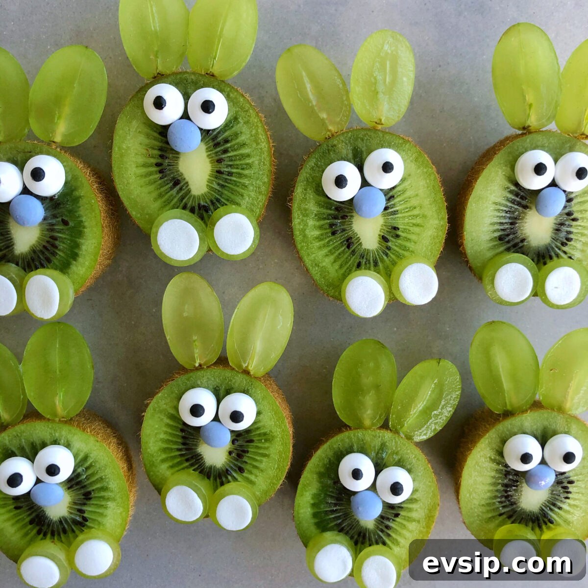 Cute Easter Bunny Fruit Platter Ideas for Spring Parties 2 Slices of kiwi decorated with candy eyes, blue sprinkle noses, and grape halves as ears are arranged to resemble bunnies.