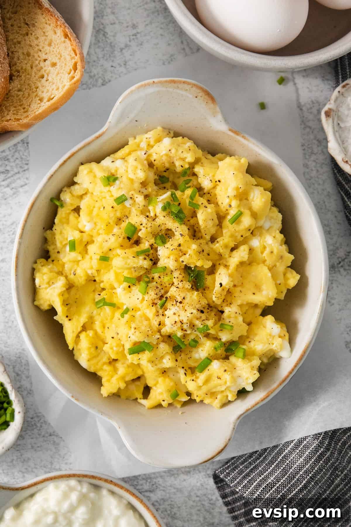 Scrambled eggs with chives and bread on a table.