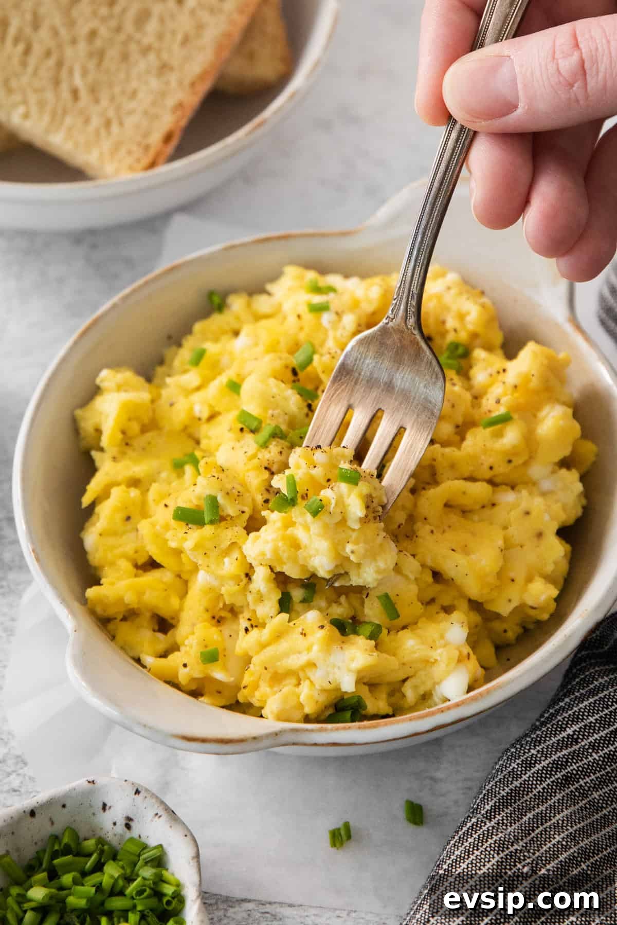 Scrambled eggs with chives in a bowl.