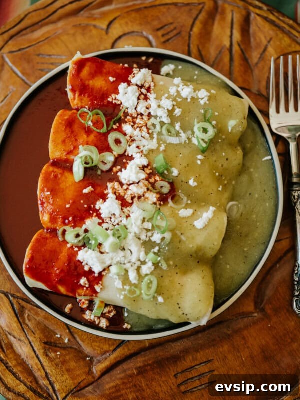 Authentic Green Enchiladas (Enchiladas Verdes) Recipe for Dinner 16 overhead shot of a dark plate with 4 enchiladas divorciadas with the left half coated in red chile sauce and the right half coated in salsa verde.