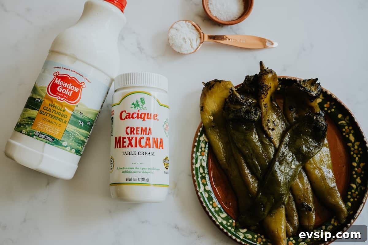 Authentic Green Enchiladas (Enchiladas Verdes) Recipe for Dinner 5 Flat lay of fresh ingredients for creamy green enchilada sauce, including roasted green chiles, onion, flour, suero (whey), and crema, arranged on a white surface.