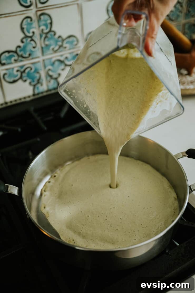 Authentic Green Enchiladas (Enchiladas Verdes) Recipe for Dinner 8 Action shot of creamy green enchilada sauce being poured into a skillet to heat, showing the rich texture of the blended roasted chile mixture.