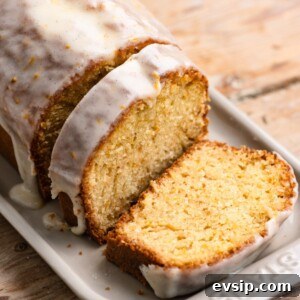 Vanilla glazed orange loaf cake on a serving platter with two slices cut.