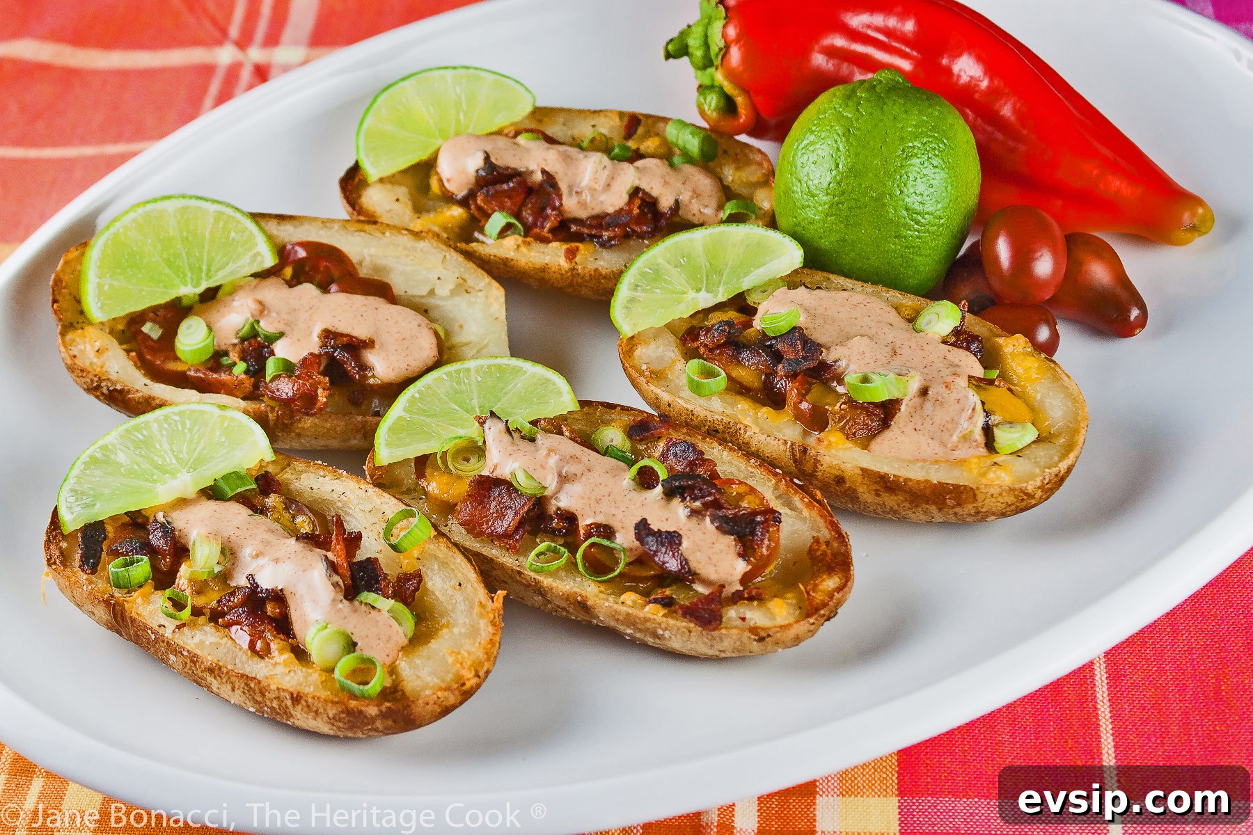 Stuffed Green Chile Potato Skins with Melted Cheese & Bacon 2 Baked potatoes are split lengthwise with the centers hollowed out and filled with crumbled bacon, green chiles, tomatoes, and melted cheese. Topped with green onions and a drizzle of taco cream. Served with lime wedges. © 2023 Jane Bonacci, The Heritage Cook.