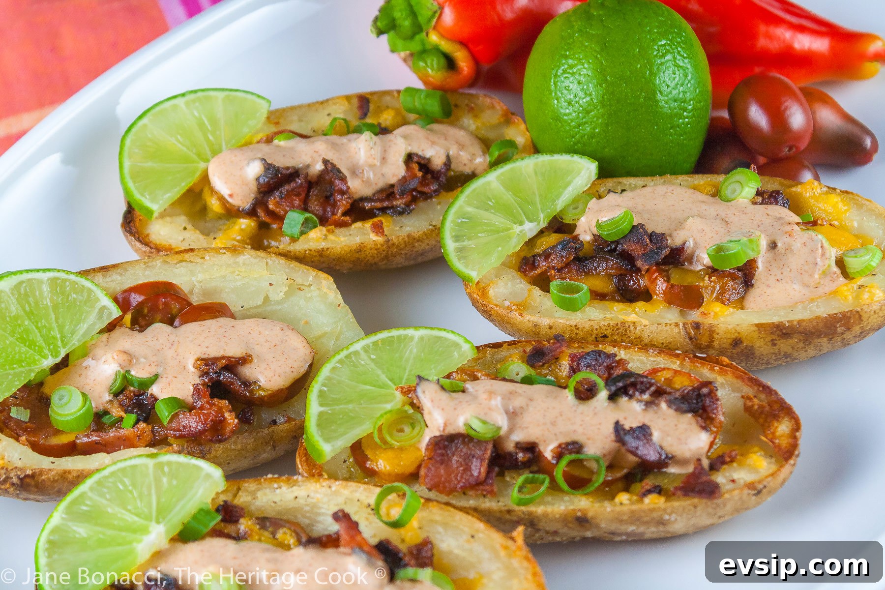 Stuffed Green Chile Potato Skins with Melted Cheese & Bacon 7 Baked potatoes are split lengthwise with the centers hollowed out and filled with crumbled bacon, green chiles, tomatoes, and melted cheese. Topped with green onions and a drizzle of taco cream. Served with lime wedges. © 2023 Jane Bonacci, The Heritage Cook.