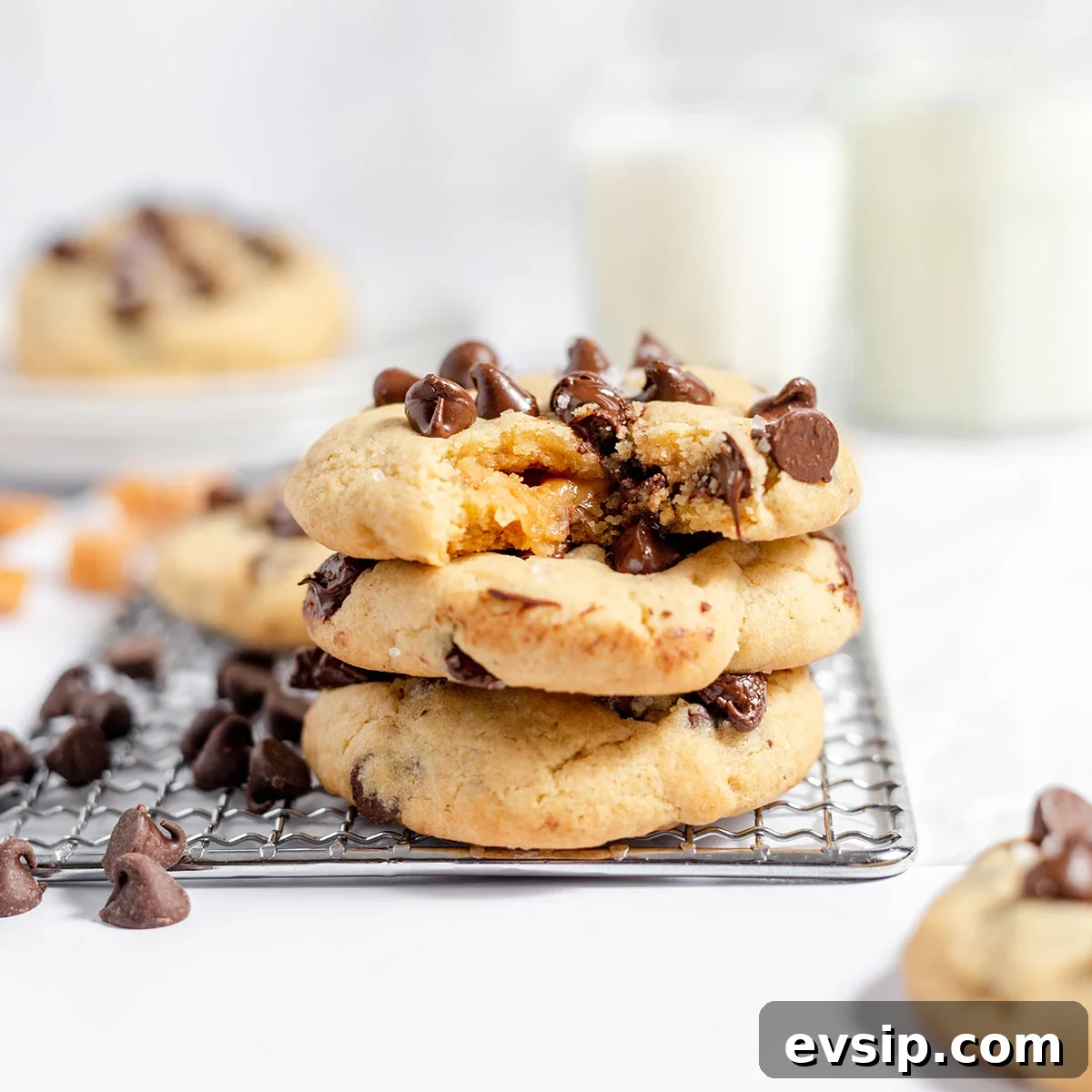 Three Caramel stuffed chocolate chip cookies stacked on wire rack.