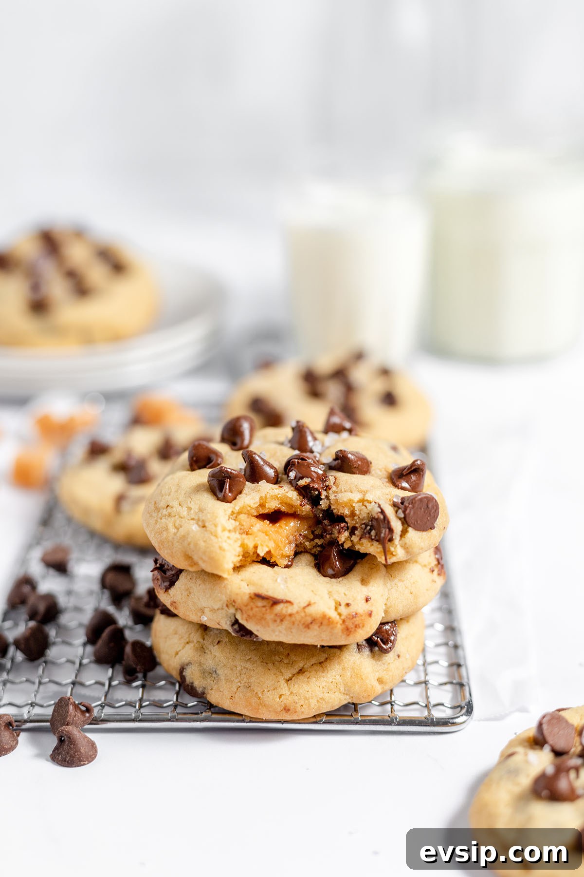 Caramel stuffed cookies with chocolate chips stacked on a wire rack.